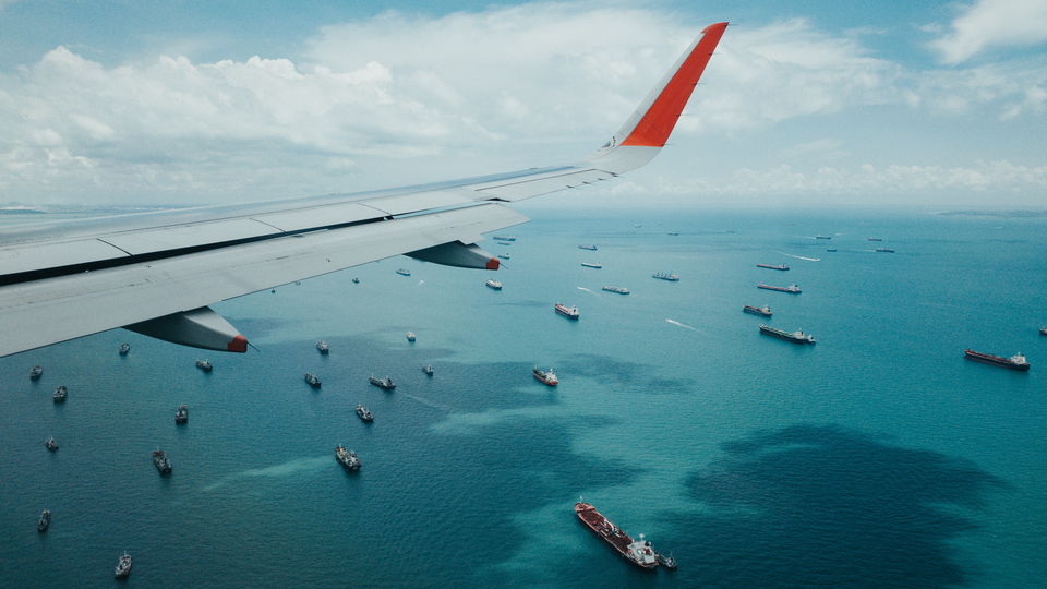Flygplansvinge och utsikt över båtar på ett hav