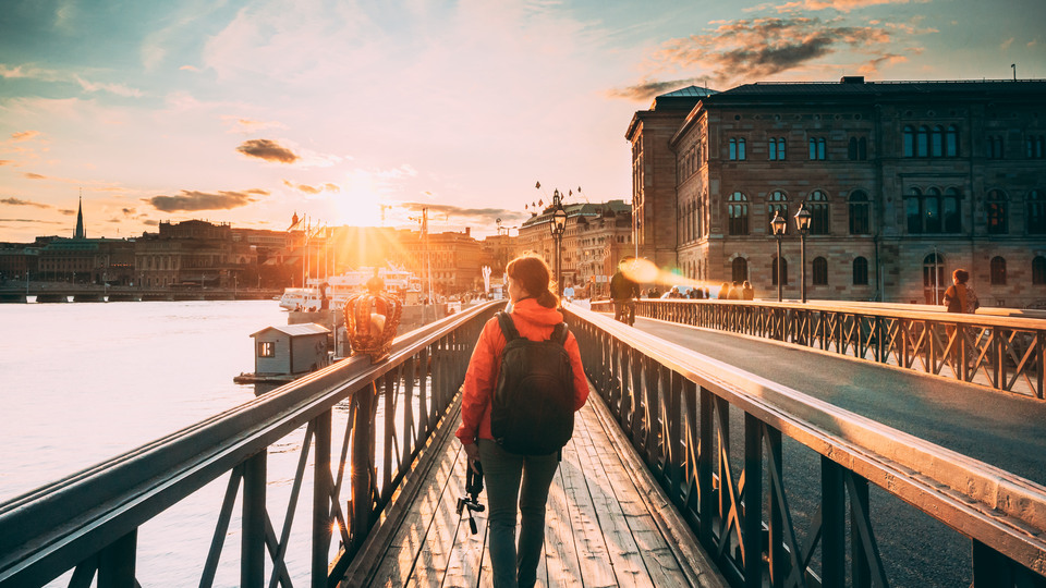 Stockholm, Sweden. Young Caucasian Woman Lady Tourist Traveler Walking On Famous Skeppsholmsbron - Skeppsholm Bridge. Popular Place, Landmark And Destination In Stockholm, Sweden.