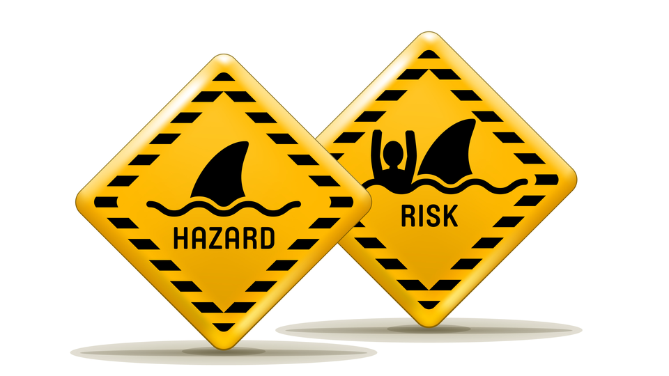 Two yellow warning signs: one with a shark fin and the text "Hazard", the other with a man in the water close to the shark fin and the text "Risk".