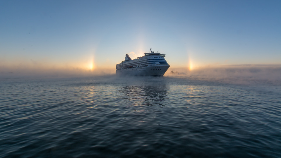 Ett stort fartyg färdas över Östersjön. med soluppgång i bakgrunden.